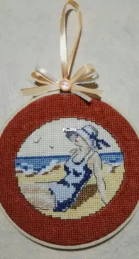 Cross stitch painting of a woman sunbathing on the beach. Design by Veronique Enginger