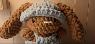 A little bunny amigurumi wearing light blue clothes